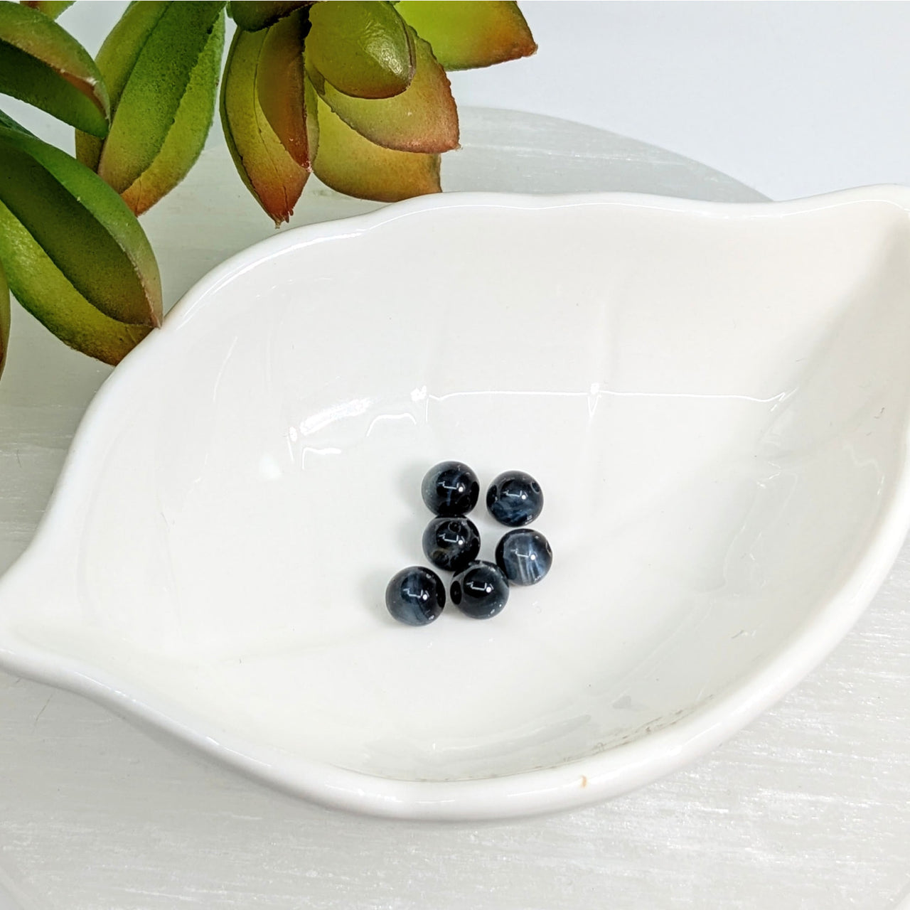 White leaf-shaped dish with blueberries and Blue Tiger’s Eye 6mm Round Beads Pack