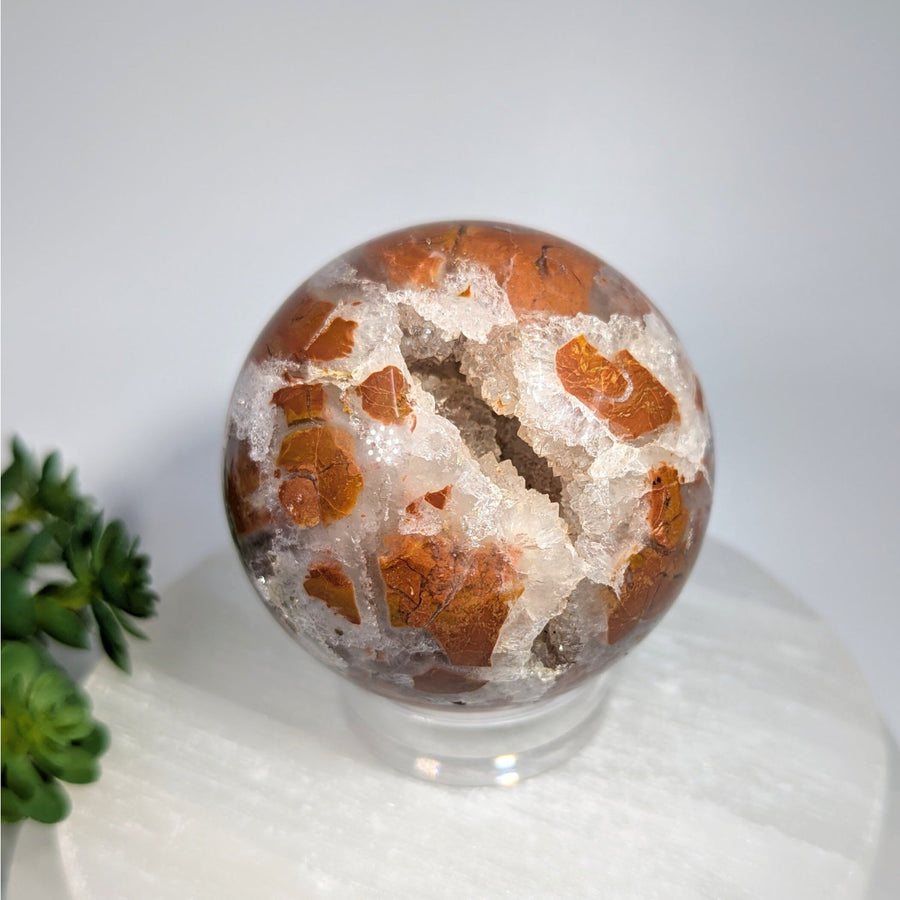 Polished orange and white brecciated jasper quartz sphere with geode interior on clear stand, 2.5 inches, #BC0606