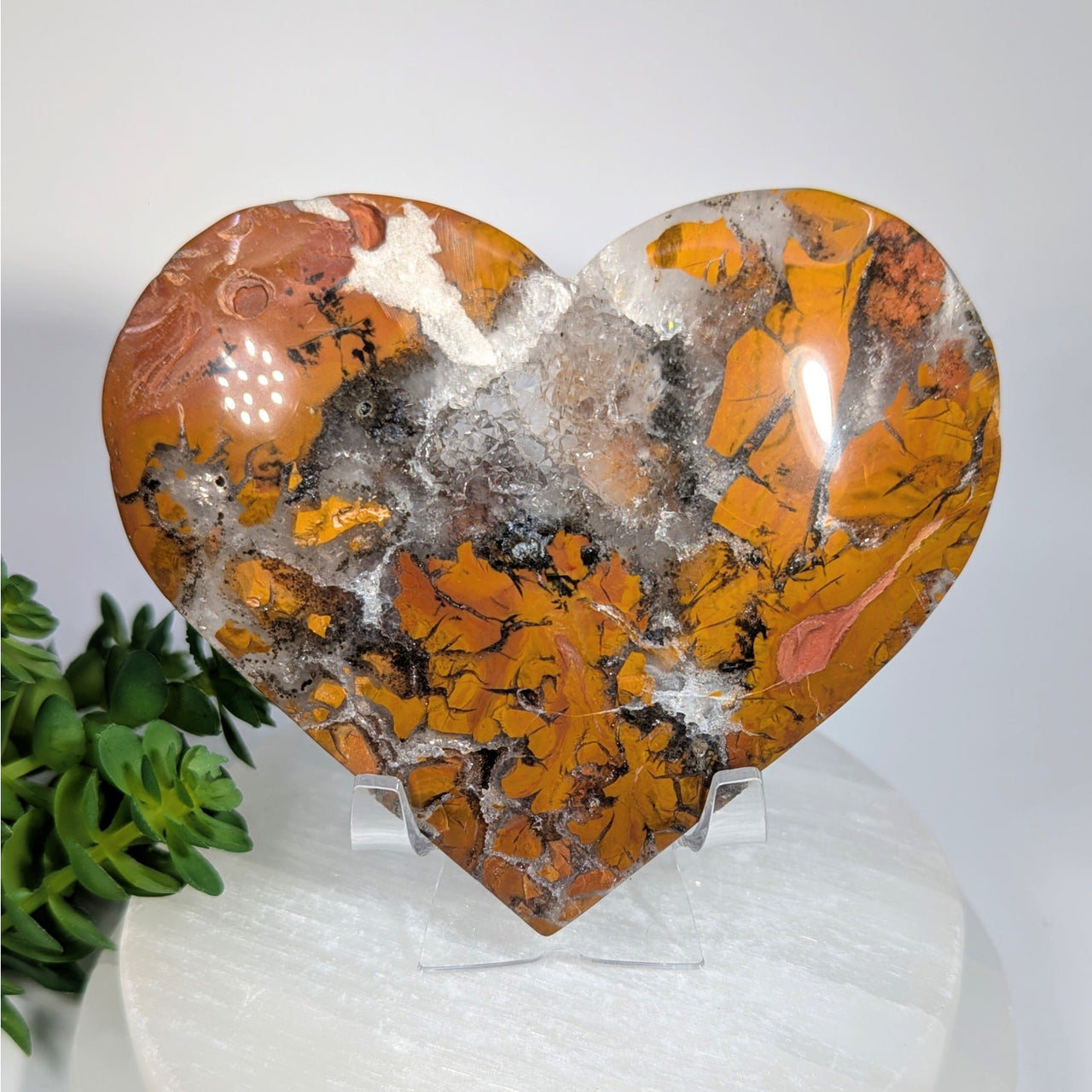Polished brecciated jasper heart stone in orange, black, white on acrylic stand