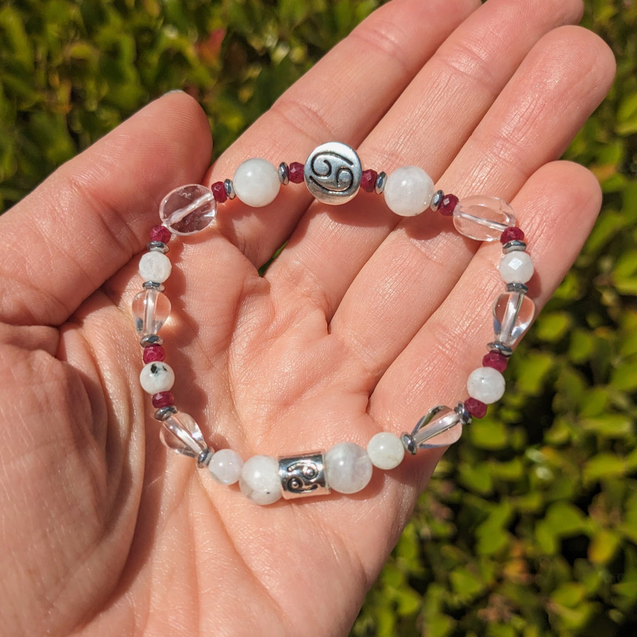 Hand holding Cancer Zodiac Handmade Beaded Bracelet with white and red beads