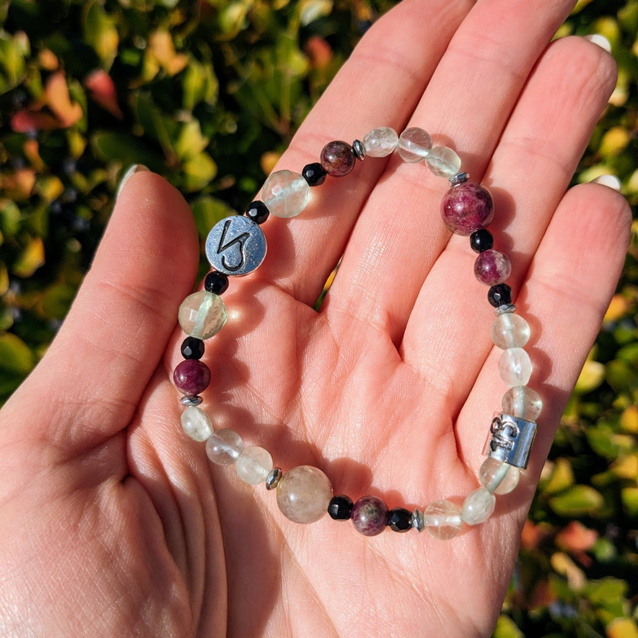 Hand holding Capricorn Zodiac Beaded Bracelet with faceted gems and astrology sign charms