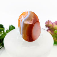 Orange and white carnelian agate 2.1-inch palm stone on display stand #BC0069