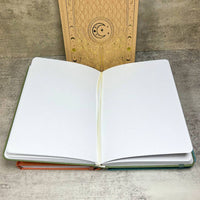 Open teal and coral Celestial Nature journal with white pages, leather cover
