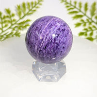 Polished 1.6-inch purple charoite sphere #BC0913 with white veining on crystal stand
