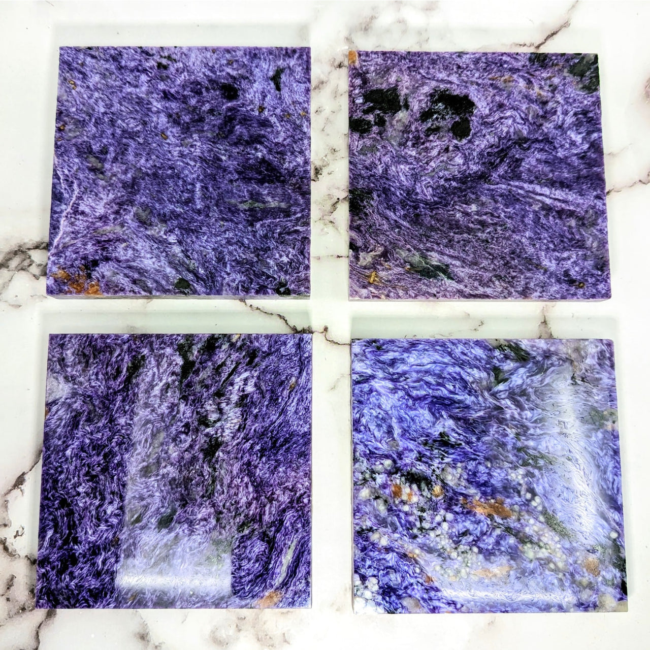 Charoite 4.5’ square tile slabs on a marble counter, perfect for stylish home decor