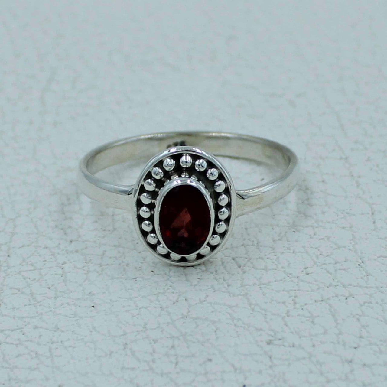 Oval faceted garnet sterling silver ring with bezel and beaded detailing