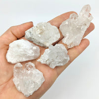 Thumbnail for A hand holding five clear quartz crystals from the Clear Quartz 1.5’ Mini Cluster collection