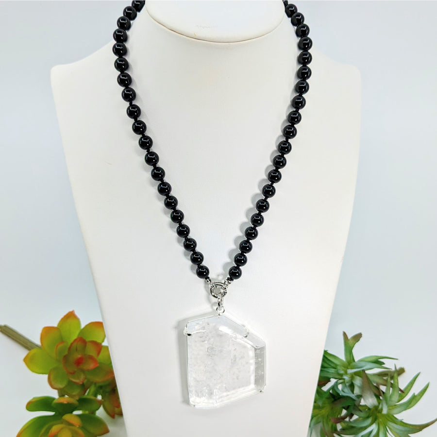 Black beaded necklace with a clear crystal pendant on the Clear Quartz Slice Pendant Onyx Necklace