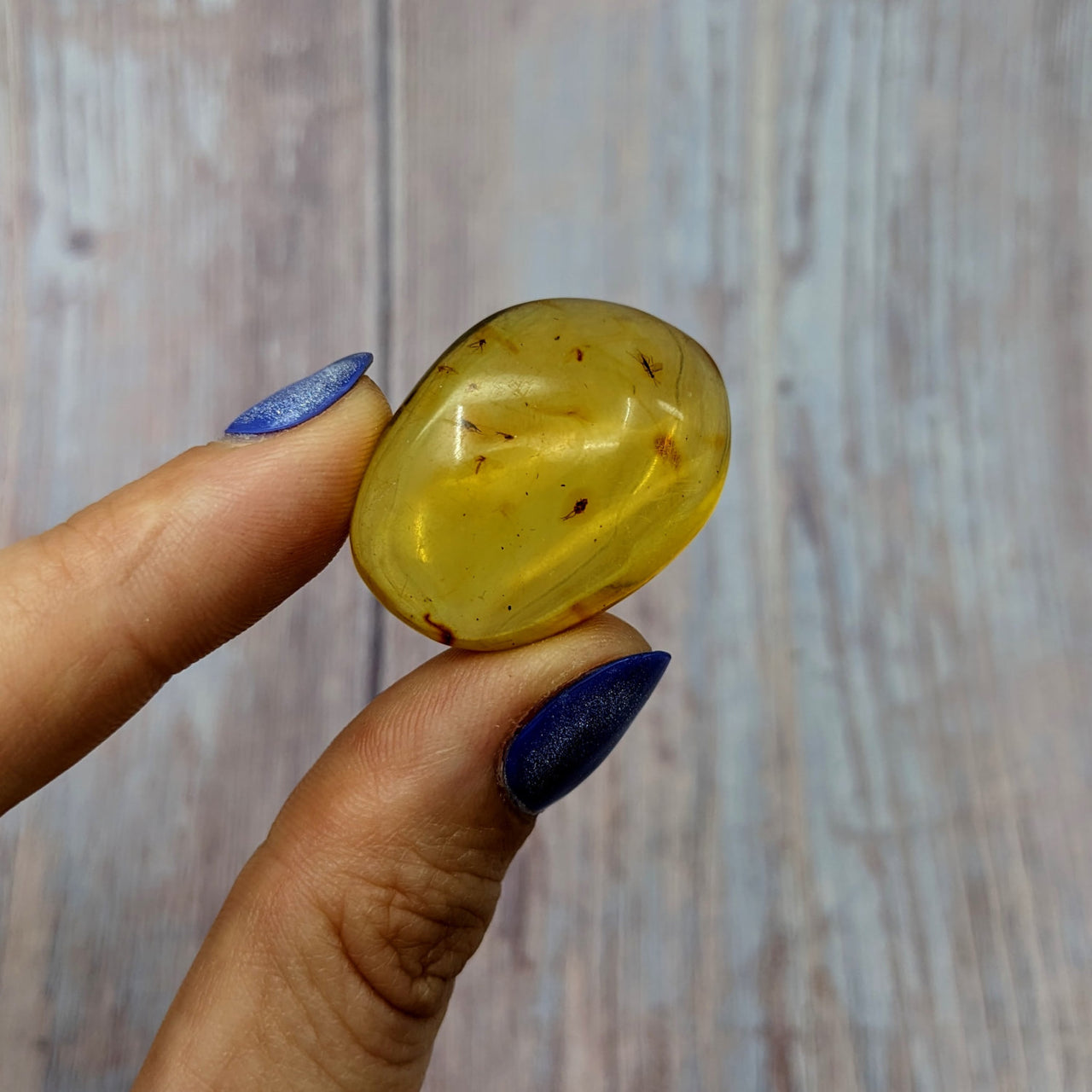 Person holding yellow Colombian Amber tumbled stone #SK9922 in their hand