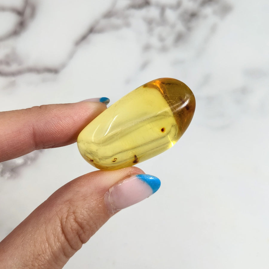 Hand holding a yellow pill from Colombian Amber 1.6’ Polished Piece #LV3153