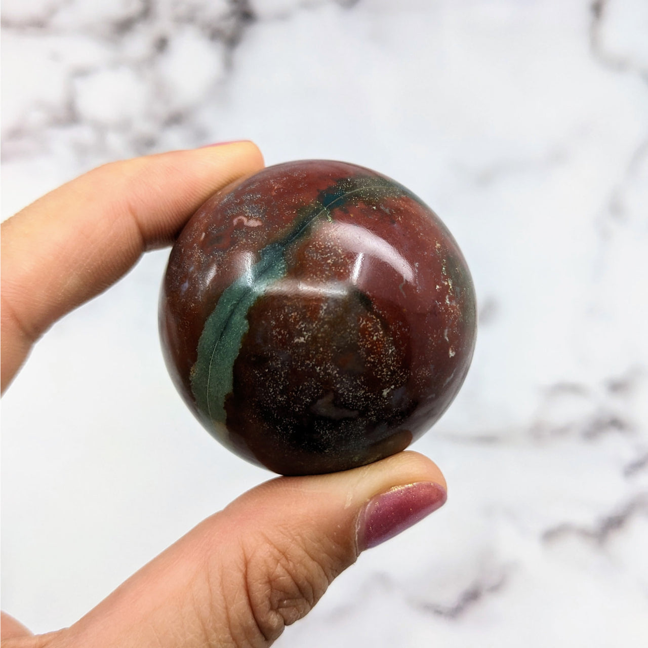 Hand holding Colorful Bloodstone Sphere #S062 with vibrant red and green patterns