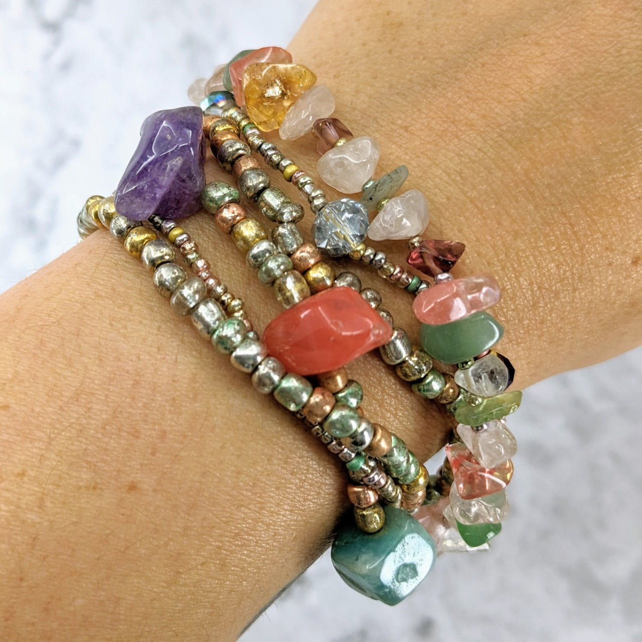 A woman’s arm adorned with Crystal Beaded Bracelet featuring green aventurine and clear quartz