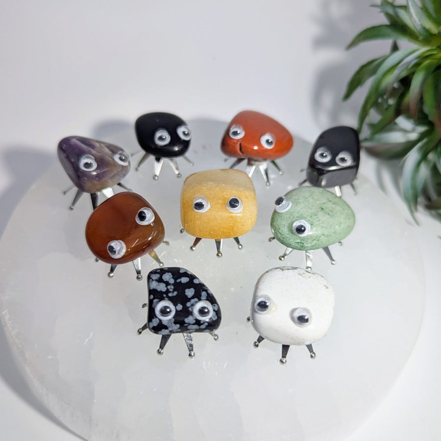 Collection of gemstone creatures with googly eyes and metal legs from Crystal Bug Pet Rock series