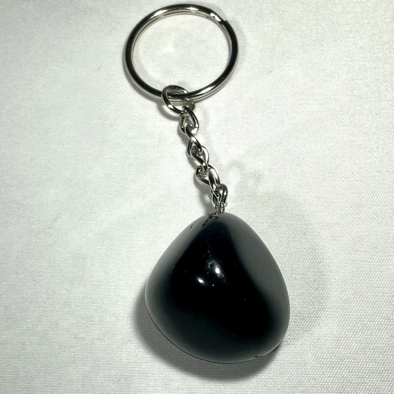 Black teardrop-shaped crystal keychain with smooth glossy finish and silver metal chain and ring for everyday use