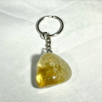 A translucent yellow citrine crystal keychain with smooth triangular shape and silver metal ring and chain from crystal keychain assorted Q106