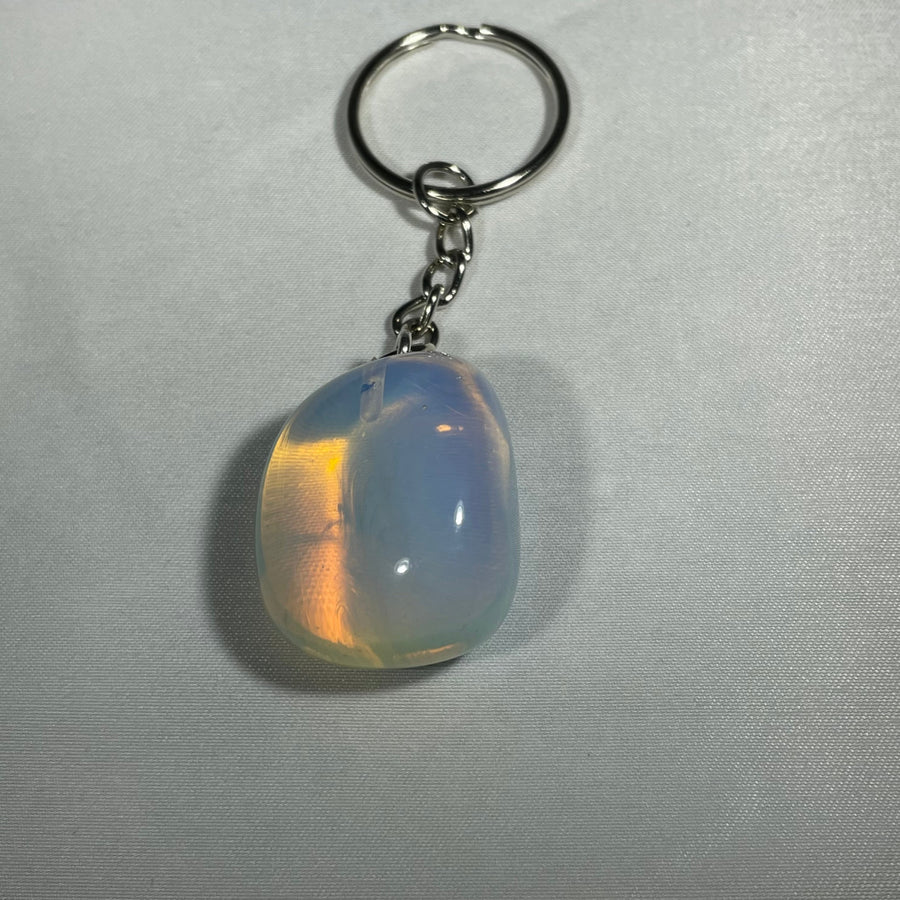 A smooth teardrop-shaped opal crystal keychain with a silver-toned metal ring and chain for everyday use