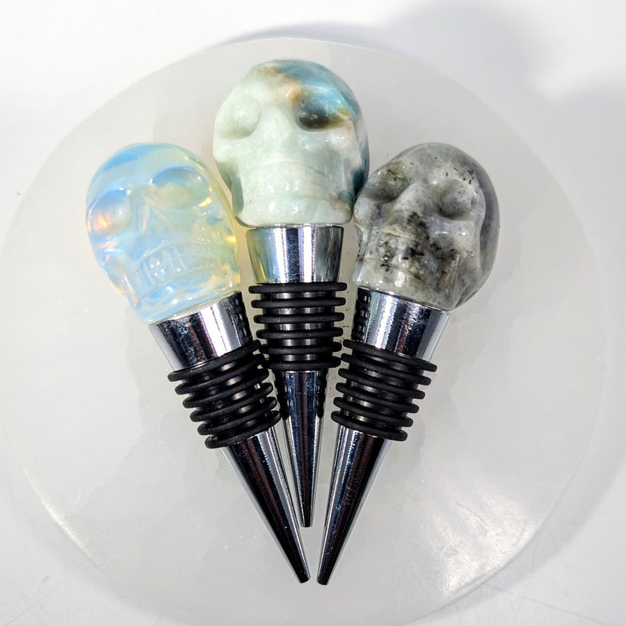 Three crystal skull wine stoppers with gemstone heads and silver bases