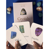 Hand holding three crystal cards: blue beryl, green emerald, purple sugilite in Crystals For Beginners Oracle Deck #LV9582