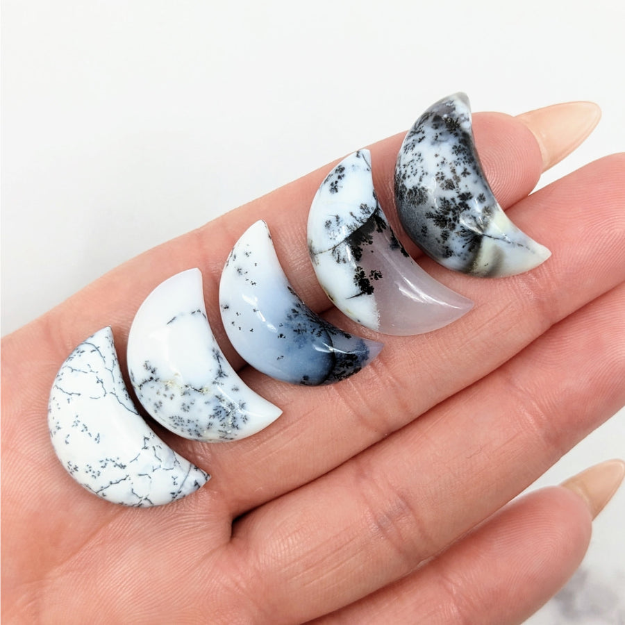 Hand holding Dendrite Agate Crescent Moon rings with black and white marble designs