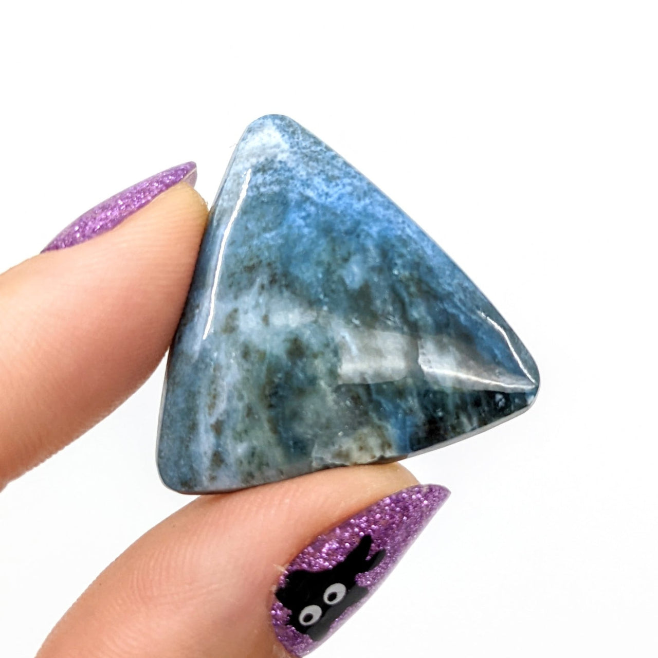 Person holding Dianite Grade AA 1.2’ Cabochon (6g) #LV1236 blue and purple stone