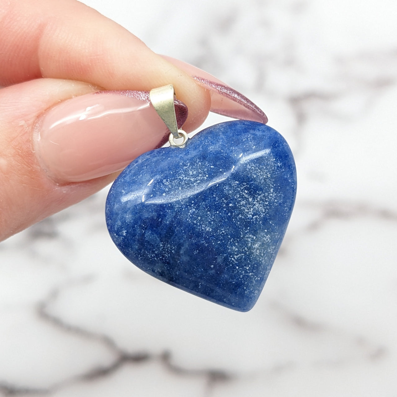 Person holding Dumortierite 1’ Heart Pendant, a blue heart-shaped stone, #SK9867