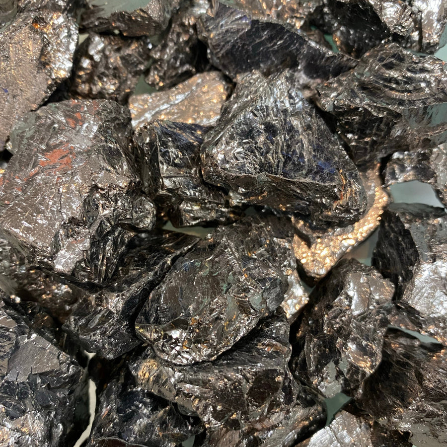 Elite noble shungite rough black metallic ore chunks with reflective surfaces and subtle golden flecks