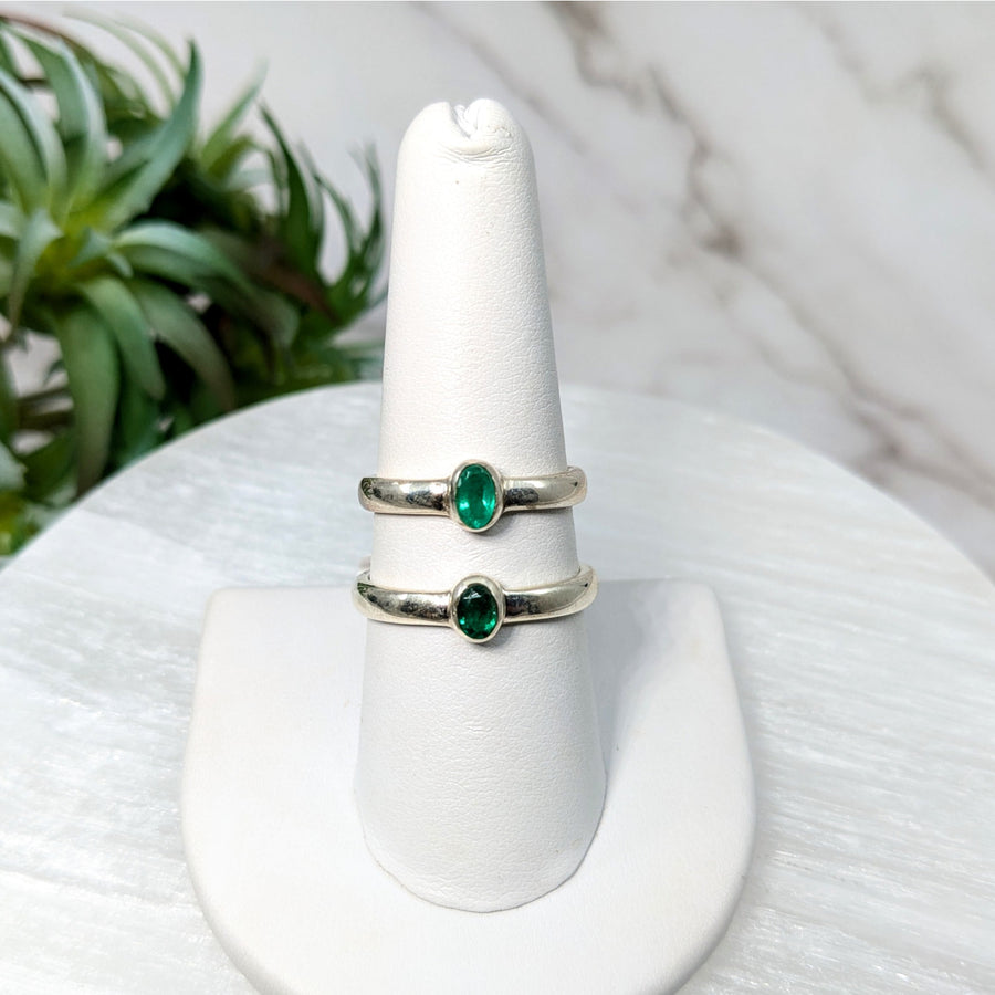Silver rings with oval green emerald gemstones in a jewelry product display