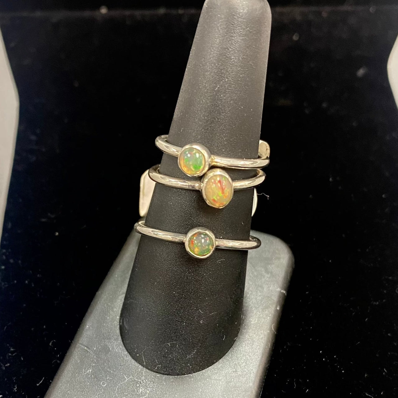 Three delicate sterling silver rings with Ethiopian Opal gemstones on a ring holder