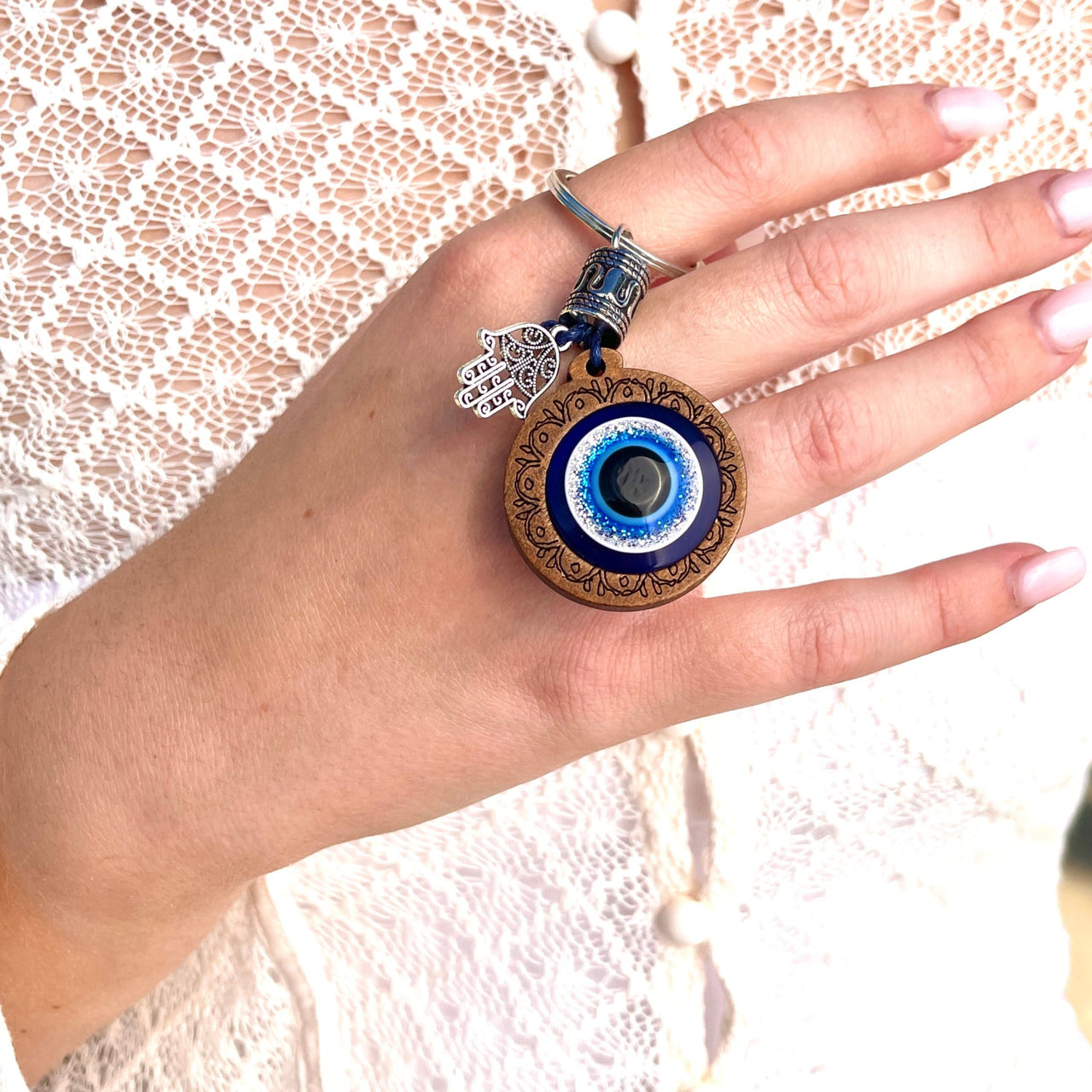 A woman wearing a white lace top and a blue eye charm from Evil Eye Keychain #Q198