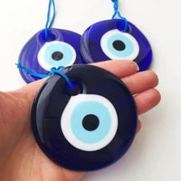 Thumbnail for A hand holding two blue and black plastic eyes from Evil Eye Wall Hangings #Q224