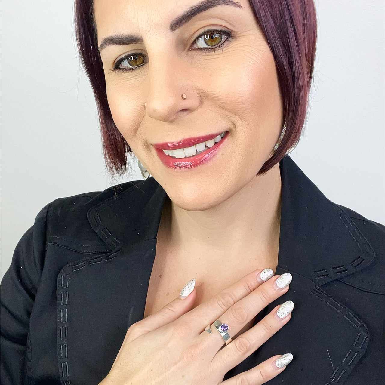 A woman with purple hair wearing a black jacket and Balaam Jewelry’s sterling silver spiral ring