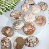 Polished oval flower agate gemstones with brown cream and orange layers on white plate for jewelry and crystals