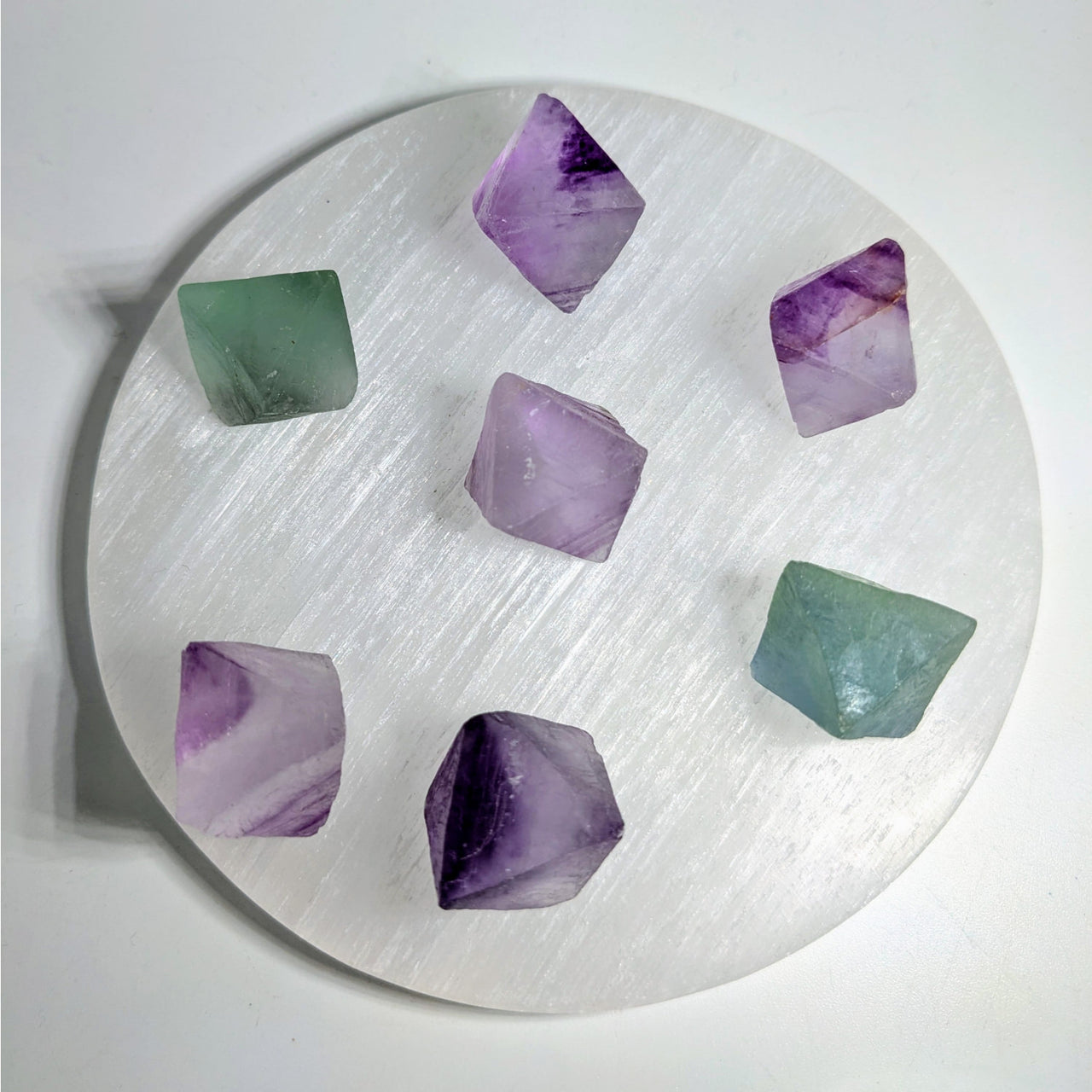 Circular white plate with purple fluorite octahedron and green crystals artfully arranged