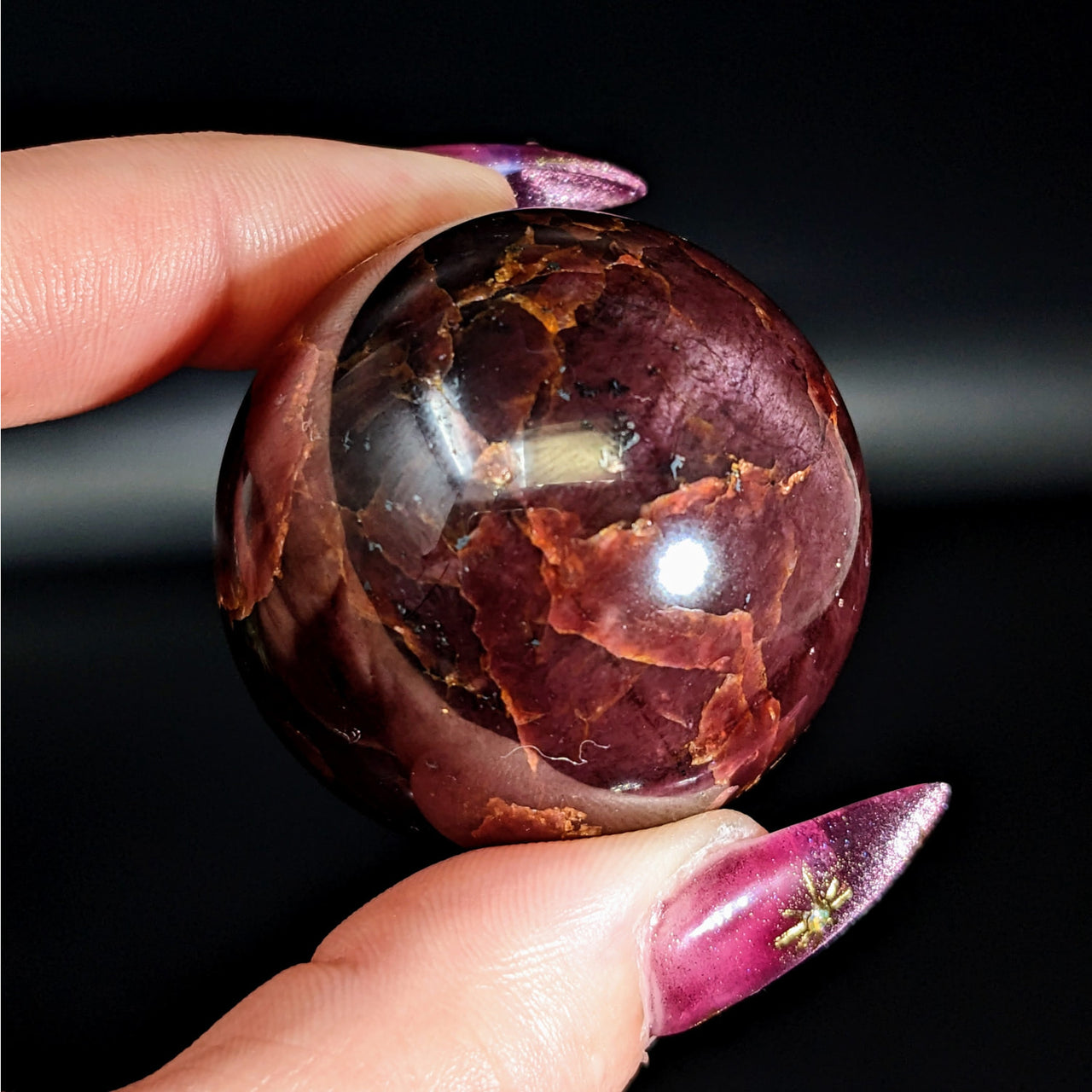Person holding the Garnet Sphere #LV4575, a large and vibrant purple stone