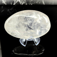 A translucent oval girasol quartz jumbo pebble with internal crystalline patterns on a clear acrylic stand