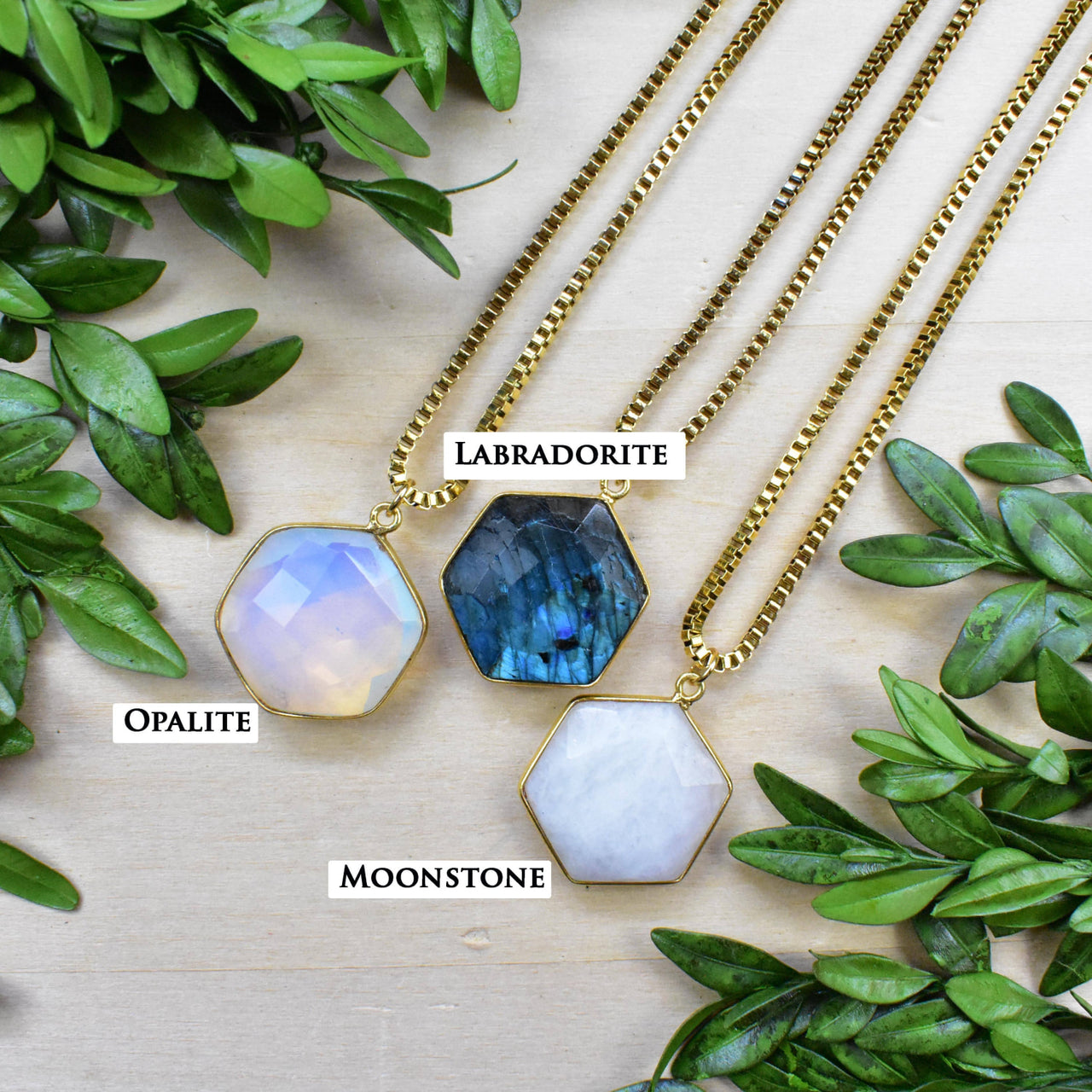 Three faceted hexagonal gemstone pendants on gold box chains: labradorite, opalite, moonstone