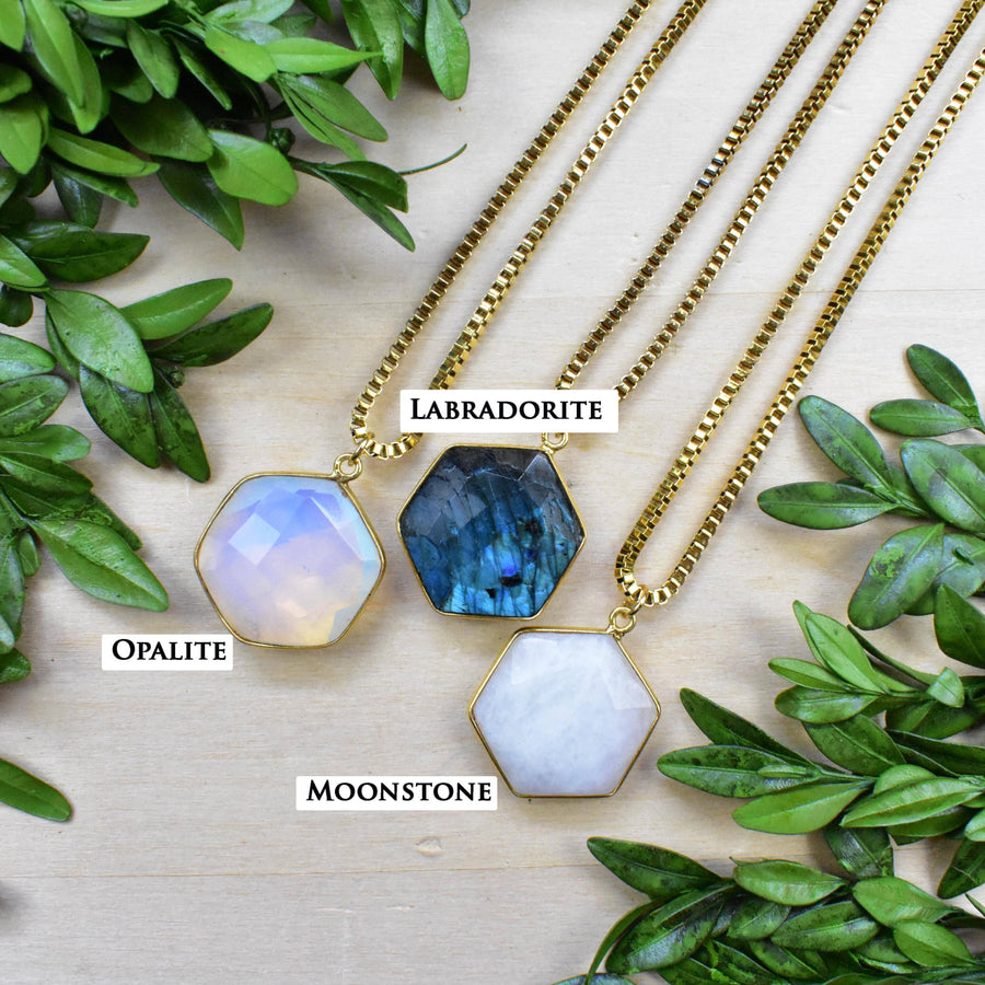 Three faceted hexagonal gemstone pendants on gold box chains: labradorite, opalite, moonstone