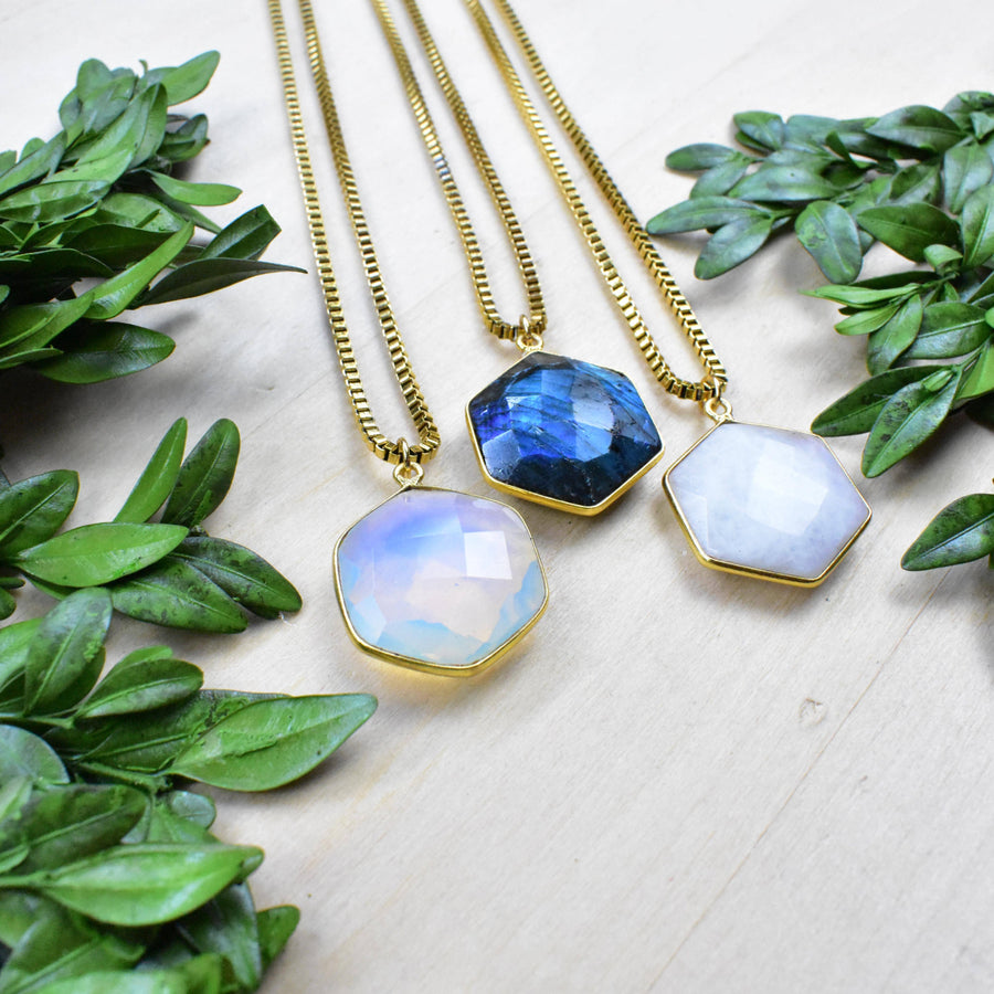 Three gold faceted hexagon gemstone necklaces in blue, opal white, translucent