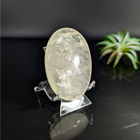 Translucent oval-shaped Gold Optical Calcite 2.4-inch palm stone displaying natural crystal clarity
