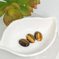 Thumbnail for Three polished gold tiger’s eye 18mm oval beads on a white ceramic dish