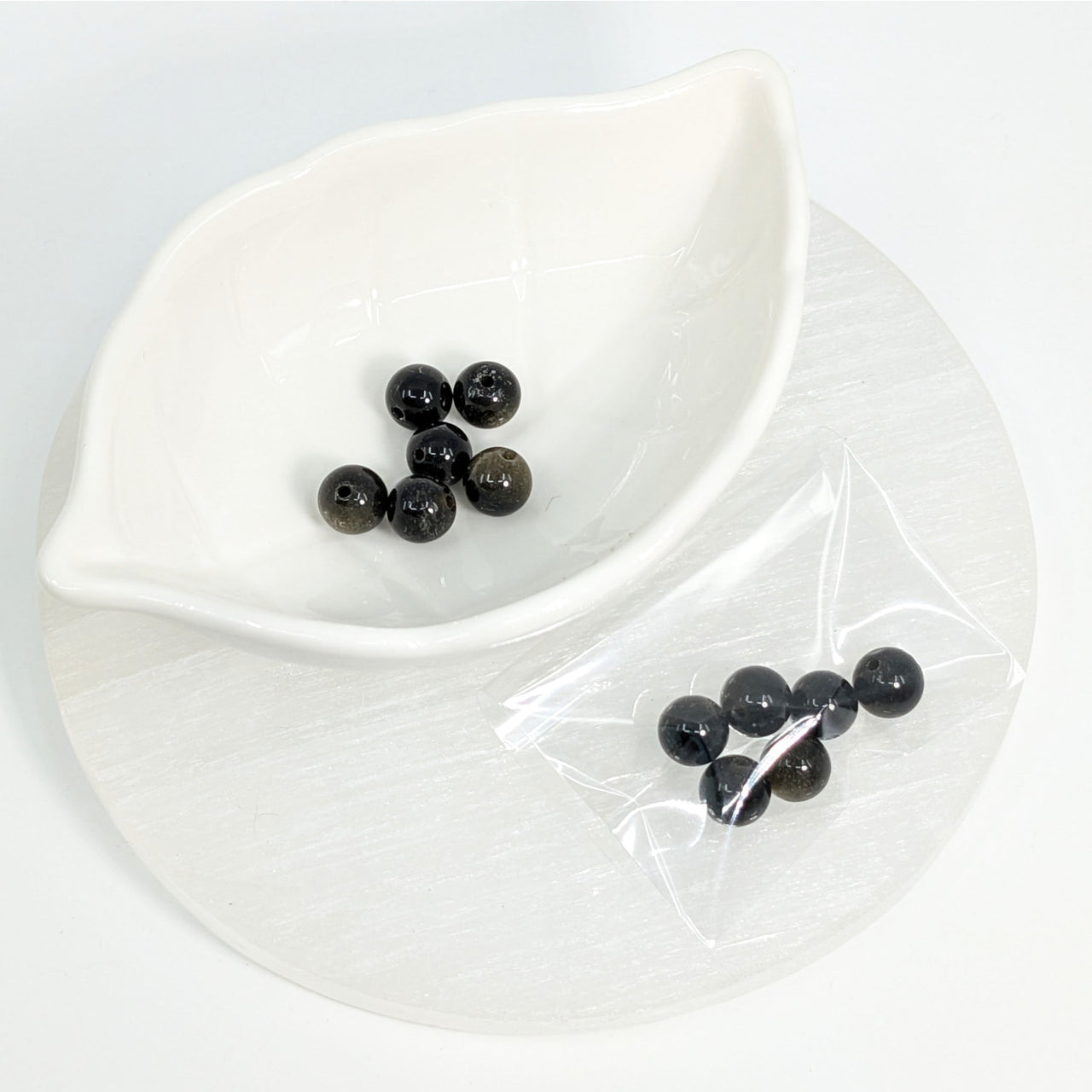 Goldsheen Obsidian 9mm round beads displayed in a white leaf-shaped dish