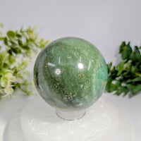 Green aventurine 2.7 inch polished sphere with golden flecks displayed on a clear acrylic stand