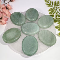 Seven smooth oval green aventurine 2in thumb stones on white plate #BC0759