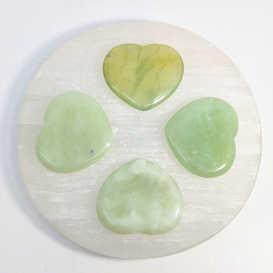 Four green heart-shaped Jade stones on a white disc for the Green Jade Thumb Heart Stone