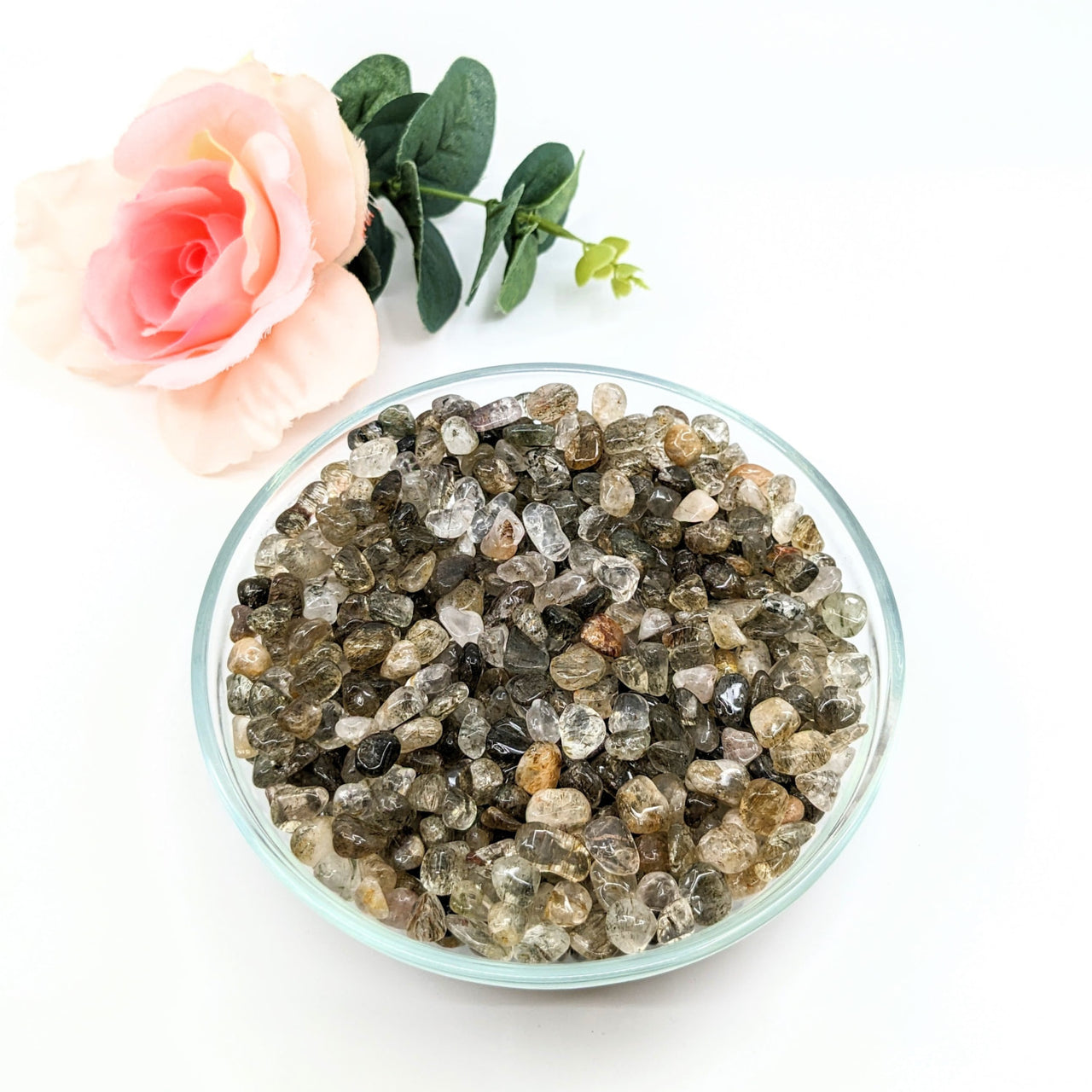 A bowl of green and white crystals next to a rose - Green Tourmaline Gravel Mini Chips