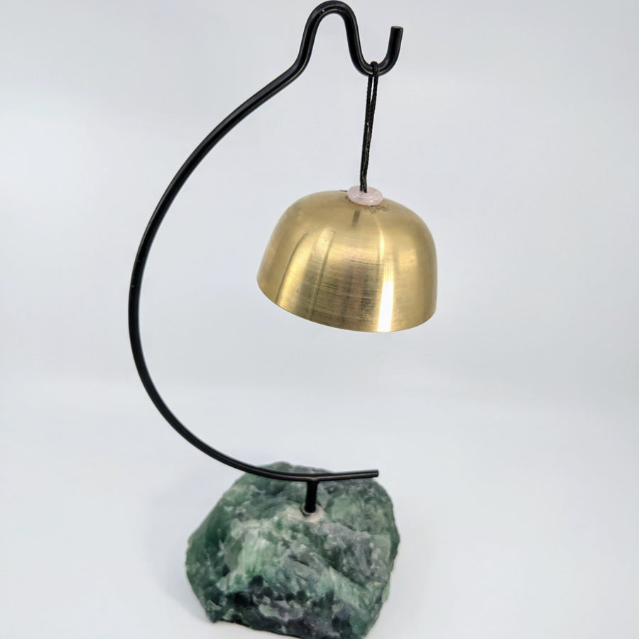 Brass bell hanging on black stand with green Fluorite stone base for Singing Bowl display