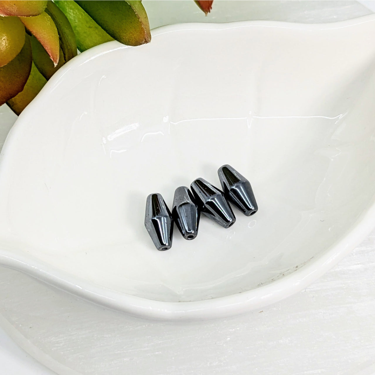 Four dark metallic Hematite 12mm Tube beads with faceted surfaces in a pack