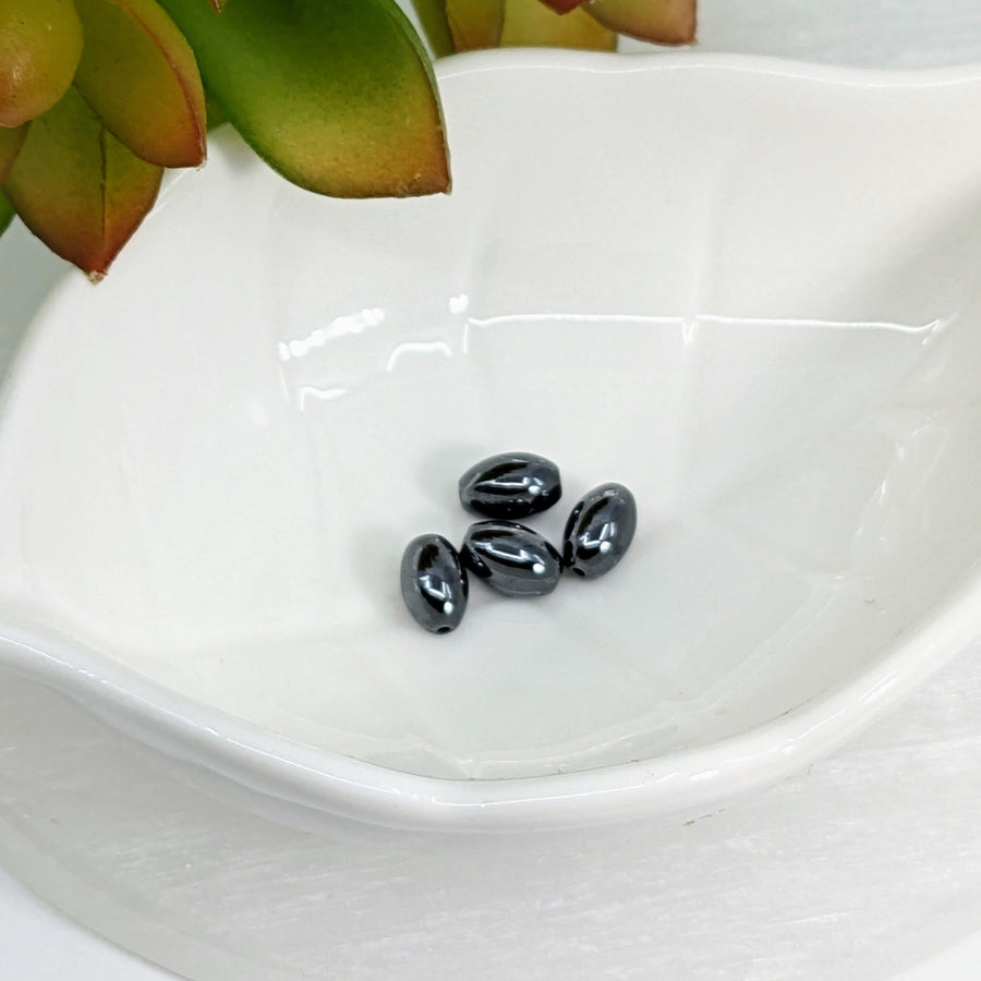 Four shiny Hematite 8mm oval beads in a pack of 4, perfect for jewelry making
