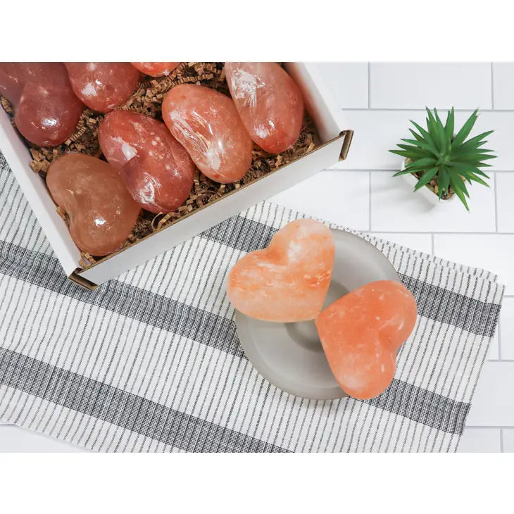 White bowl with pink Himalayan salt and a heart-shaped Himalayan massage stone