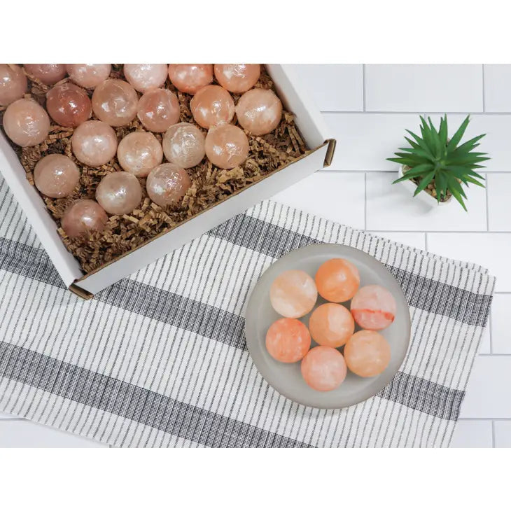 Himalayan salt massage ball next to eggs and fruit on a table for natural wellness